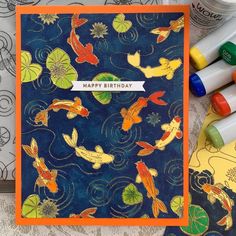 a birthday card with waterlilies and koi fish on it, surrounded by crayons