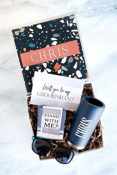 a gift box with coffee, sunglasses and other items in it on a marble surface