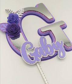 a purple cake topper with the number six on it and flowers in the middle