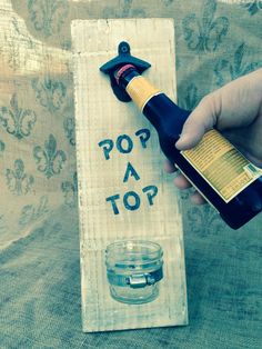 a person holding a bottle of wine near a sign that says pop top on it