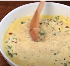 a wooden spoon in a white bowl filled with soup