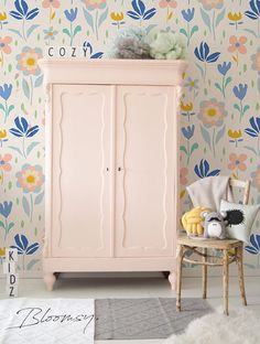 a pink armoire sitting next to a wallpapered room with flowers on it