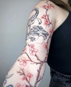 a woman's arm covered in tattoos with birds and cherry blossoms on the arm