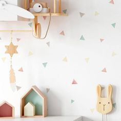 a white wall with colorful triangles on it and a wooden toy in the foreground