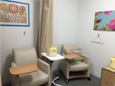 a hospital room with two chairs, a table and a baby crib in it