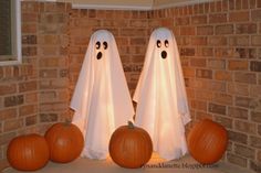 two pumpkins sitting on top of a table with ghost faces