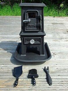 an old fashioned stove sitting on top of a wooden deck next to other tools and gadgets