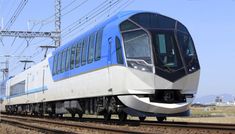 a blue and white train traveling down tracks next to power lines on a sunny day