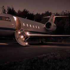 an airplane sitting on the runway at night with its lights on and it's door open