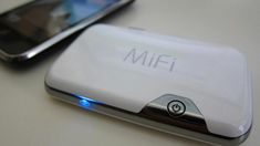 two cell phones sitting next to each other on top of a white table and one has the word mifi written on it