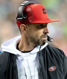 a close up of a man wearing a red and black hat with a pipe in his mouth