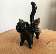 a black cat figurine with a butterfly on it's back sitting on top of a wooden table