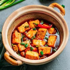 a pot filled with tofu and sauce on top of a green napkin next to some vegetables