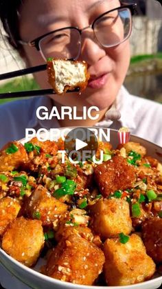 a woman eating food with chopsticks in her mouth and looking at the camera