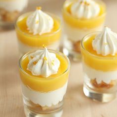 small desserts with whipped cream and orange sauce in glass cups on wooden table top