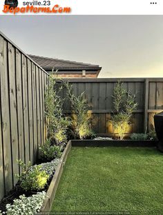 a small backyard with grass and plants in the back yard, next to a fence