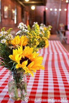 sunflowers and daisies are arranged in vases on a table with red and white checkered tablecloth