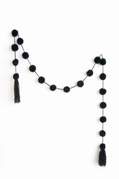 a black beaded necklace with tassels hanging from it's sides on a white background