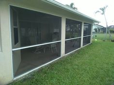 an enclosed patio area with chairs and tables on the grass next to a fenced in yard