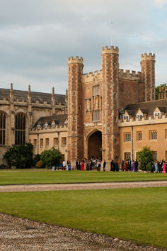 a group of people standing in front of a large castle like building with tall towers