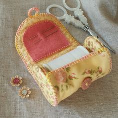 a pair of scissors sitting on top of a piece of fabric next to sewing needles