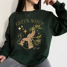 This Green Witch sweatshirt is the perfect thing to wear while casting spells, growing herbs, or just being the badass witch you are! Gildan sweatshirts are UNISEX SIZES and have a traditional, loose fit. Size up for that trendy oversized look! Medium-heavy fabric gives this sweatshirt beautiful drape and body. We recommend laying a favorite top flat and measuring it before ordering to get the perfect fit. PLEASE WASH BEFORE WEARING - items may feel slightly stiff when you receive them. This is Green Witch Clothes, Garden Witch Outfit, Green Witch Aesthetic Outfit, Forest Witch Aesthetic Fashion, Garden Witch Aesthetic, Green Witch Aesthetic Fashion, Hedge Witch Aesthetic, Green Witch Outfit