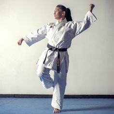 the woman is practicing her karate moves on the blue mat in front of the wall