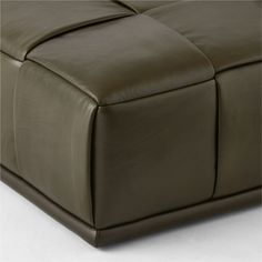 a close up view of the back end of a brown leather couch with square shaped cushions