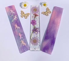 three bookmarks with flowers, butterflies and daisies on them are laying next to each other