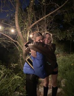 two women hugging each other in the woods at night