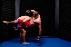 a man in red shorts is doing a handstand on a blue mat with one leg up