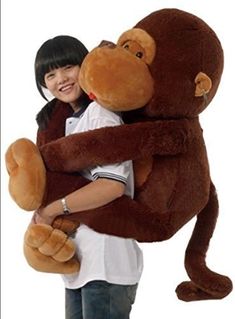 a girl holding a large stuffed monkey in her arms and hugging it's face