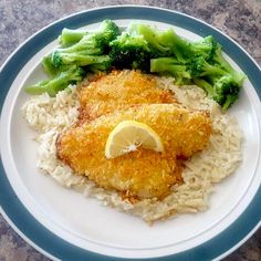 a plate with chicken, rice and broccoli on it next to a lemon wedge