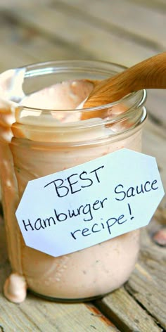 a jar filled with sauce sitting on top of a wooden table next to a spoon