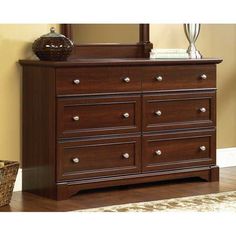 a brown dresser sitting in front of a mirror on top of a hard wood floor