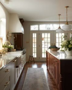 a large kitchen with wooden floors and white walls, along with an open door leading to the outside