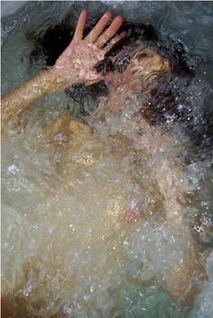 a man is swimming in the water with his hand up to his face and head