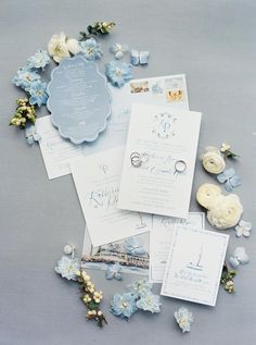 the wedding stationery is laid out on top of each other, with blue and white flowers