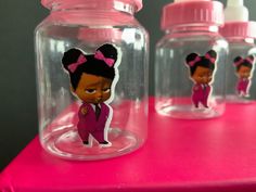 three glass jars filled with cartoon figures on top of a pink tablecloth covered table