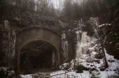 an old tunnel in the woods with snow on the ground