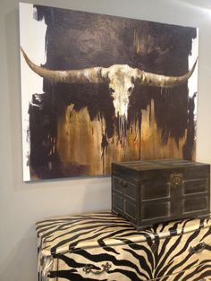 a cow skull on top of a zebra print ottoman in front of a large painting