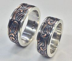 two wedding rings with intricate designs on each one, set against a plain white background