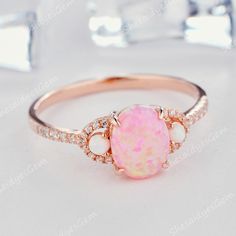 a pink opal and diamond ring on a white surface with some diamonds around it