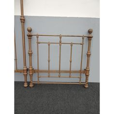 a bed frame made out of wood and metal with two posts on each side, against a gray wall