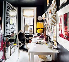 a room with black walls and pictures on the wall, along with a white desk