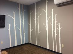 an empty room with trees painted on the wall and a flat screen tv mounted to the wall