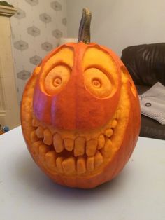 a carved pumpkin with an evil smile on it's face, sitting on a table