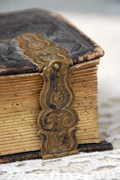 an old book is sitting on top of the carpeted floor and it's cover has intricate designs