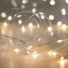 a string of lights that are on top of a wooden table with blurry lights in the background