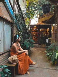 a woman in an orange dress sitting on a bench